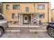 Apartment Building with a covered entryway, brick facade, and parking area with various vehicles at 1182 Clermont St # A202, Denver, CO 80220