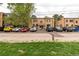 Apartment Building featuring a brick facade, covered entryway, and ample parking in a green surrounding at 1182 Clermont St # A202, Denver, CO 80220