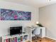 Office area with a white desk, gray chair, a modern TV and an abstract fish painting over a bookcase at 1182 Clermont St # A202, Denver, CO 80220