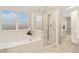 Bright bathroom showcasing a soaking tub and glass-enclosed shower, with a view to the walk-in closet at 13744 W 86Th Dr, Arvada, CO 80005