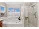 Bathroom with soaking tub and glass-enclosed shower stall, enhanced by a large window for natural light at 13744 W 86Th Dr, Arvada, CO 80005