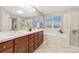 Bright bathroom features a double vanity, soaking tub, and a glass-enclosed shower with updated fixtures at 13744 W 86Th Dr, Arvada, CO 80005