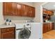 Laundry room featuring a side-by-side washer and dryer, wood cabinets and view into the kitchen at 13744 W 86Th Dr, Arvada, CO 80005