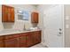 Mudroom featuring a utility sink, white door, wood cabinets, and natural light from the window at 13744 W 86Th Dr, Arvada, CO 80005