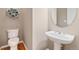 Powder room featuring a modern pedestal sink, round mirror, and decorative floral wall decor at 13744 W 86Th Dr, Arvada, CO 80005