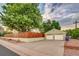 View of detached two car garage with white doors and concrete driveway in a fenced yard with mature trees at 488 S Leyden St, Denver, CO 80224