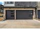 Close-up of attached garages with black doors and stone facade at 2321 Lakeshore Ln # 10, Superior, CO 80027