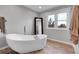 Bright bathroom with a freestanding tub, wood floors, large window, and full length mirror at 10822 Eagle Crest Ct, Parker, CO 80138