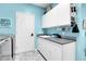 Bright laundry room with white cabinets, modern appliances, blue accent wall, and patterned flooring at 10822 Eagle Crest Ct, Parker, CO 80138