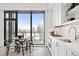 Modern kitchen with white cabinetry, marble backsplash, and stainless steel appliances, complemented by a dining area and city view at 1750 Wewatta St # 1825, Denver, CO 80202