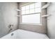 Clean and modern bathroom featuring a bathtub with tiled walls, built-in shelving, and ample natural light at 13152 E 104Th Dr, Commerce City, CO 80022