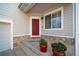 Inviting front porch with red door, matching planters and stone veneer on the home's facade at 13152 E 104Th Dr, Commerce City, CO 80022