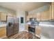 Galley kitchen features stainless steel appliances, wood-look flooring, and light wood cabinetry at 13152 E 104Th Dr, Commerce City, CO 80022
