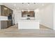 Modern kitchen with stainless steel appliances, center island with sink and pendant lights, and wood-look flooring at 5726 N Jebel Way, Aurora, CO 80019