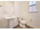Stylish powder room featuring a pedestal sink, modern toilet, and natural light from the window at 11452 Autumn Moon St, Littleton, CO 80125