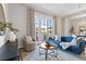 Bright living room features a modern blue sofa, round wooden table, and large windows with access to a private balcony at 410 Acoma St # 309, Denver, CO 80204