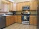 Kitchen features stainless steel appliances, natural wood cabinets and tile flooring at 19421 E Evans Dr, Aurora, CO 80013