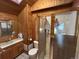 Bathroom featuring wood paneling, sink, toilet, and shower with glass door, offering a rustic charm at 2602 Jasmine St, Denver, CO 80207