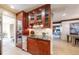 Stylish wet bar area with wine fridge, glass shelving, custom cabinets, and granite countertops at 5432 S Dayton Ct, Greenwood Village, CO 80111