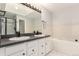 Bright bathroom featuring double sinks, a large mirror with vanity lights, and separate tub and shower at 1633 S Trenton St, Denver, CO 80231