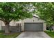 Inviting home exterior with a lush lawn, mature tree, and a gray two-car garage at 1633 S Trenton St, Denver, CO 80231