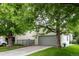 Picture of house exterior with a green lawn, mature trees and a gray two-car garage at 1633 S Trenton St, Denver, CO 80231