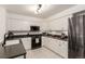 Well-lit kitchen with white cabinets, black appliances, black countertops, and tile floors at 1633 S Trenton St, Denver, CO 80231
