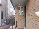 Inviting entryway with brick facade, unit number, decorative pots and a well-lit covered porch at 2323 S Jamaica St, Aurora, CO 80014