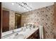 Bathroom featuring a double sink, white tile counter, and wallpapered walls at 5503 W Colorado Ave, Lakewood, CO 80232