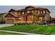 Beautiful home featuring a landscaped front yard with lush greenery, stone accents, and three-car garage at 1440 Eversole Dr, Broomfield, CO 80023