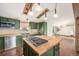 Eat-in kitchen features green cabinets, stainless steel appliances, and a butcher block island with cooktop at 7892 Beverly Blvd, Castle Pines, CO 80108