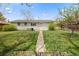 A large lush back yard with a stone pathway and garden beds near the back of the home at 8012 Zuni St, Denver, CO 80221