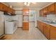 Kitchen featuring wood cabinets, white appliances, and vintage flooring at 8012 Zuni St, Denver, CO 80221
