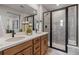 Modern bathroom with double vanity, wood cabinets, and tiled shower with glass door at 2086 Wagon Wheel Aly, Brighton, CO 80601