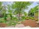 Landscaped backyard with patio seating, mature trees, and greenery creates a serene outdoor space at 2240 Summitview Dr, Longmont, CO 80504