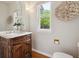 Elegant powder room featuring a wood vanity, marble countertop, stylish decor, and bright natural light at 2240 Summitview Dr, Longmont, CO 80504