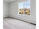 A bright bedroom featuring plush carpet, white walls, and a large window with views of a home under construction at 1416 Orchard St, Brighton, CO 80601