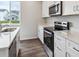 Well-lit kitchen featuring stainless steel appliances, white cabinets, quartz countertops, and a view from the window at 1416 Orchard St, Brighton, CO 80601