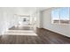 Open-concept space featuring hardwood floors, white walls, and a kitchen with white cabinets in the distance at 1416 Orchard St, Brighton, CO 80601