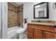 Bathroom featuring a granite-topped vanity, framed mirror, tub and shower with neutral tile and bronze fixtures at 6248 E Mineral Pl, Centennial, CO 80112