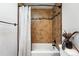 Bright bathroom showcases neutral-colored tile walls surrounding a white tub, shower, and black fixtures at 6248 E Mineral Pl, Centennial, CO 80112