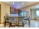 Basement bar with marble countertop, plush chairs, and custom glass and wood cabinets at 16713 W Archer Ave, Golden, CO 80401