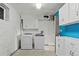 Bright laundry room with washer, dryer, white cabinets, and blue accent wall at 428 N Perry Park Rd, Sedalia, CO 80135