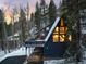 A-frame home with a large deck nestled in a snowy wooded area at dusk at 6365 Highway 9, Breckenridge, CO 80424