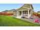 The home's backyard shows a patio, lush green grass, and a barbecue alongside outdoor toys at 16043 Fillmore St, Thornton, CO 80602