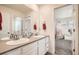 Bright bathroom featuring double sinks, white cabinetry, and a view into an adjacent bedroom at 16043 Fillmore St, Thornton, CO 80602