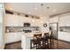 A modern kitchen boasts an island with barstool seating, pendant lights, stainless steel appliances, and white cabinetry at 16043 Fillmore St, Thornton, CO 80602