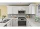Well-lit kitchen featuring white cabinets, stainless steel appliances, and gray backsplash at 1747 High Plains Ct, Superior, CO 80027