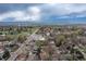 Wide aerial view showcasing the neighborhood with mature trees, streets, and distant mountain views under a cloudy sky at 3230 Vance St, Wheat Ridge, CO 80033