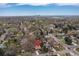 Aerial neighborhood view with mature trees, and distant city skyline, marked property location, and clear skies above at 3230 Vance St, Wheat Ridge, CO 80033